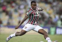 Jhon Arias, do Fluminense. Ele está chutando uma bola com o pé direito.